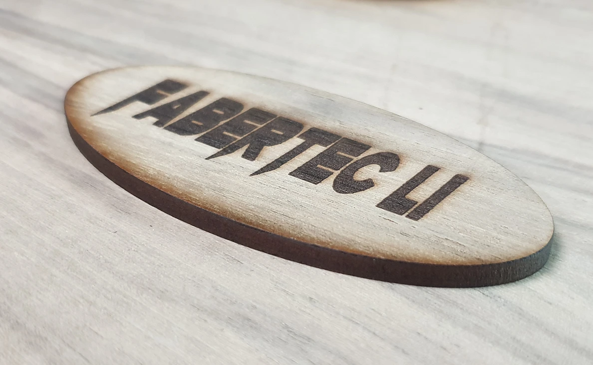 Laser cutter engraving a detailed name pattern on wood